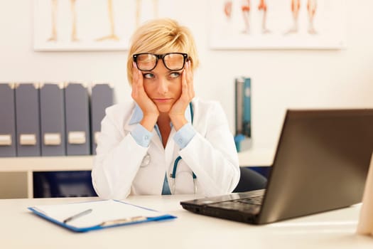 Desperate female doctor sitting at her office