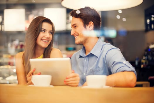 Flirting couple in cafe using digital tablet