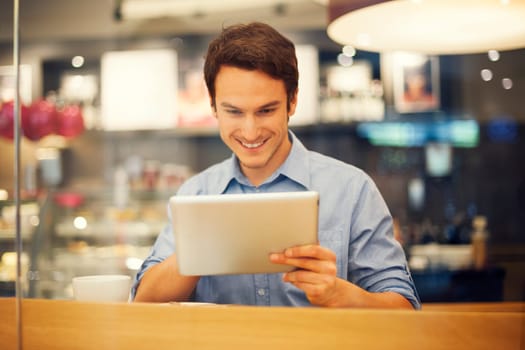 Smiling man using digital tablet in cafe
