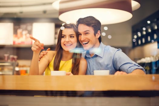 Happy young couple in cafe pointing to something