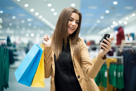 Cheerful female shopper texting on mobile phone