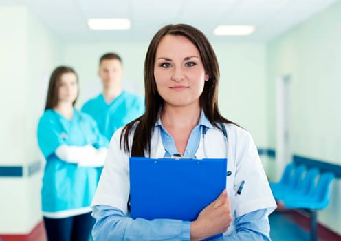 Portrait of young female doctor with interns in background