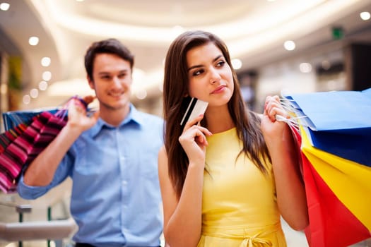 Focus young woman holding credit card and shopping bags