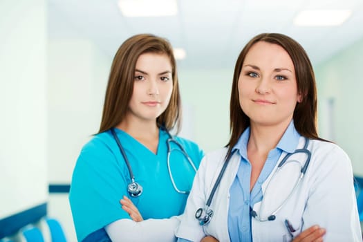 Portrait of young female doctor with intern in background