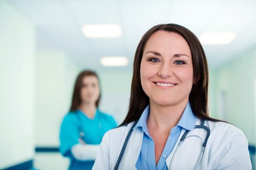 Portrait of young female doctor with intern in background