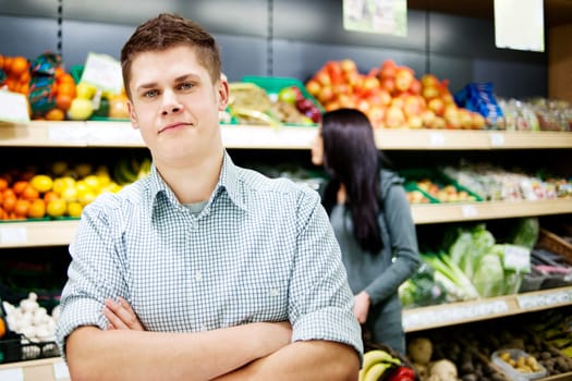 Young man standing the front of shopping shelves