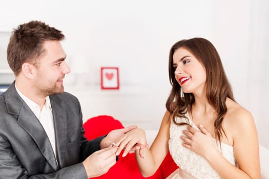 Man putting a wedding ring on his girlfriend's finger