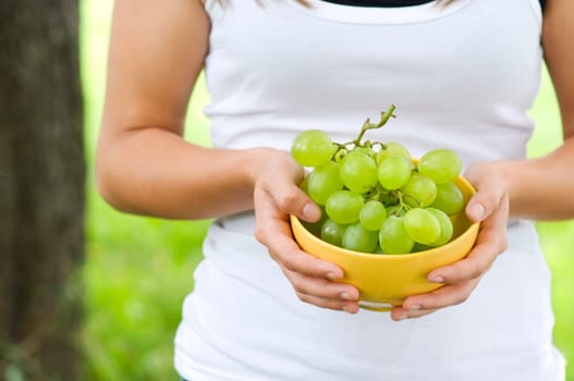 Young woman holding bowl with grapes
