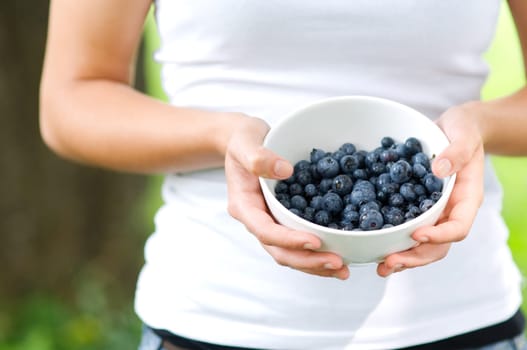 Young woman holding bowl filled blueberries