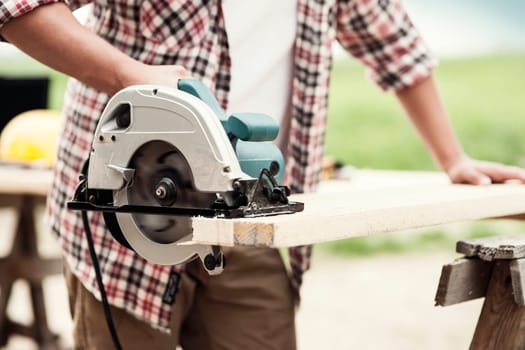 Close-up of carpenter cutting a wooden plank