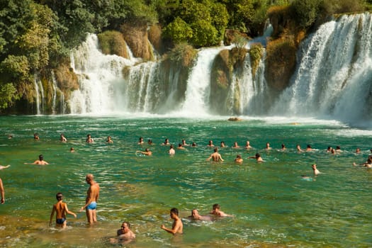 KRKA,CROATIA - AUGUST 17, 2014. Tourists enjoy a bath at Krka waterfalls in Krka National park, great attraction near Sibenik. Krka river forms 17 waterfalls in an area of 400 mt. in length and 100 mt. in width.