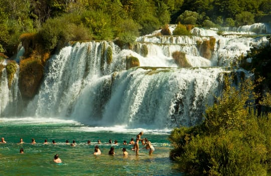 KRKA,CROATIA - AUGUST 17, 2014. Tourists enjoy a bath at Krka waterfalls in Krka National park, great attraction near Sibenik. Krka river forms 17 waterfalls in an area of 400 mt. in length and 100 mt. in width.