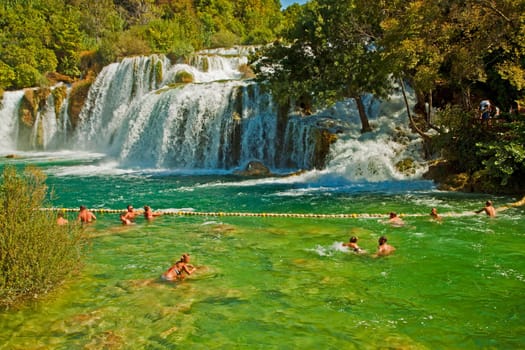 KRKA,CROATIA - AUGUST 17, 2014. Tourists enjoy a bath at Krka waterfalls in Krka National park, great attraction near Sibenik. Krka river forms 17 waterfalls in an area of 400 mt. in length and 100 mt. in width.