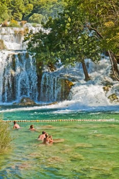 KRKA,CROATIA - AUGUST 17, 2014. Tourists enjoy a bath at Krka waterfalls in Krka National park, great attraction near Sibenik. Krka river forms 17 waterfalls in an area of 400 mt. in length and 100 mt. in width.