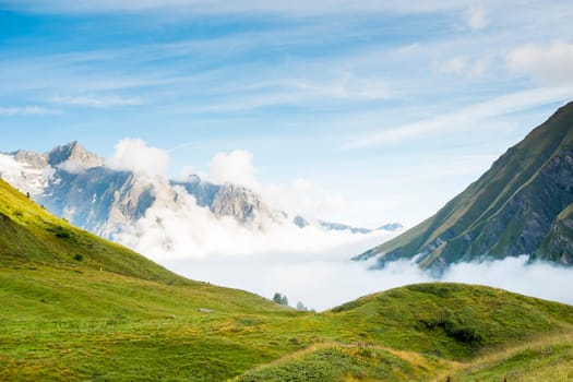 Low hanging clouds in La Peule valley, in Switzerland, with alps in the background. The region is one of the stages in the popular Mont Blanc tour, which crosses France, Italy and Switzerland.