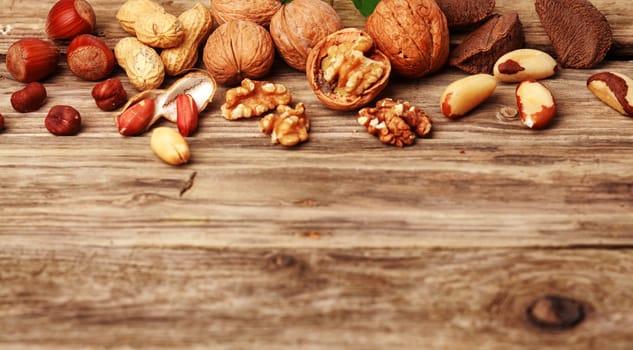 Selection of festive fresh nuts both shelled and in their shells on rustic wood with copyspace including almonds, hazelnuts, brazil nuts, peanuts and walnuts