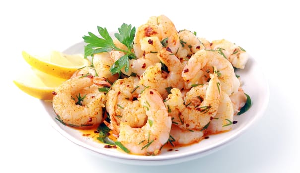 Seasoned savory pink prawns or shrimp tails grilled in fresh diced herbs and butter and served with slices of fresh lemon for a gourmet seafood starter