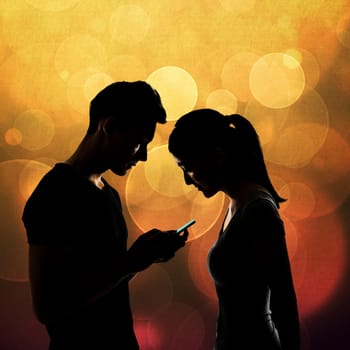 Couple using cellphone, silhouette portrait.
