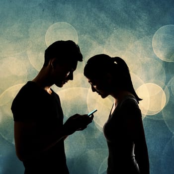 Couple using cellphone, silhouette portrait.