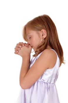 A little blond girl standing in profile with her hands folded and praying,.isolated for white background..