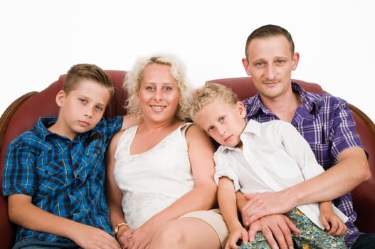 Torso portraits of two parents with their two sons,aged 7 and 13,on a brown leather sofa in front of a white wall