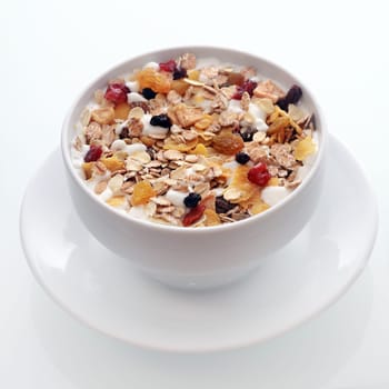 Bowl of delicious breakfast muesli with oat and wheat flakes mixed with dried fruit and nuts served in a white ceramic bowl for a healthy nutritious meal