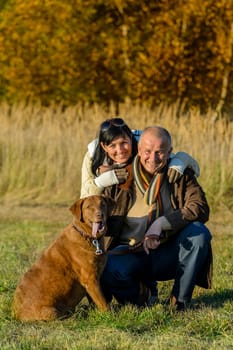 Cheerful couple with retriever dog in autumn park sunset