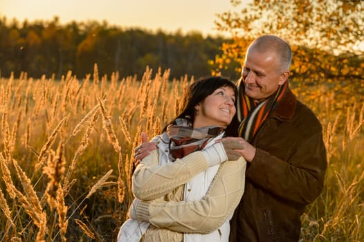 Couple in love embracing autumn sunset countryside looking each other