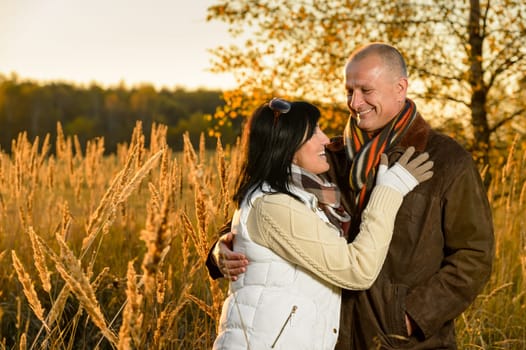 Couple in love hugging in autumn sunset countryside looking each other