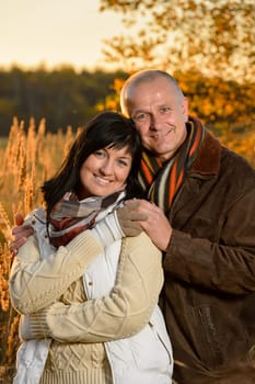 Romantic couple embracing in autumn park backlit by sunset