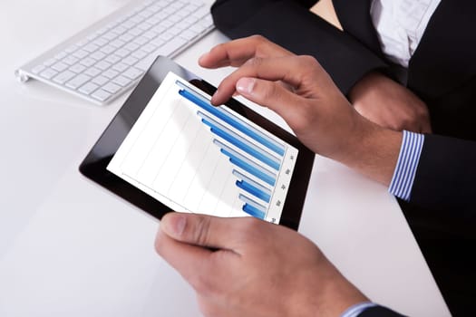 Businessman And Businesswoman Looking At Digital Tablet Showing Graph