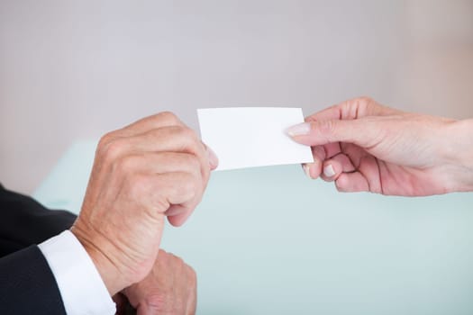 Happy Mature Businesspeople Exchanging Visiting Card In Office