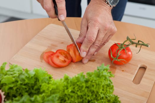 Mature Man Cutting Vegetable In The Kitchen