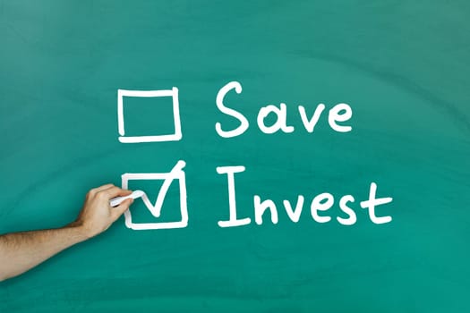 Invest instead of saving concept on green blackboard