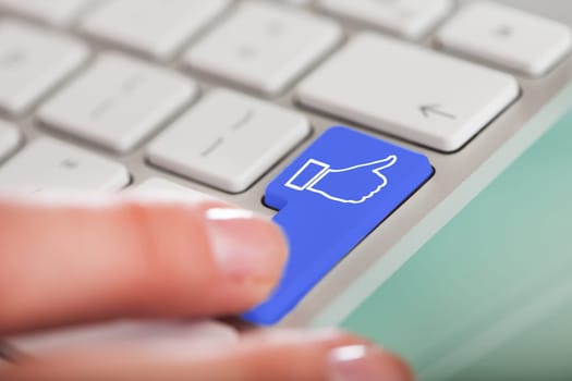 Close-up Of Finger On Enter Button With Like Icon On Computer Keyboard