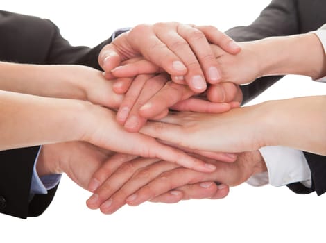 Close-up Of Businesspeople Hands Stacking Together Over White Background