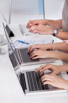 Close-up Of Businesspeople In A Row Working On Laptop