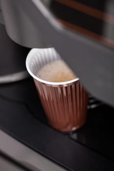 Coffee maker pouring hot espresso coffee in a glass