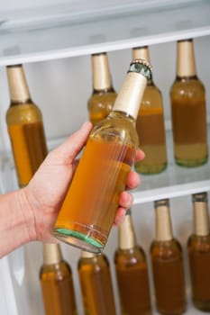 Man choosing bottle of beer from a refrigerator