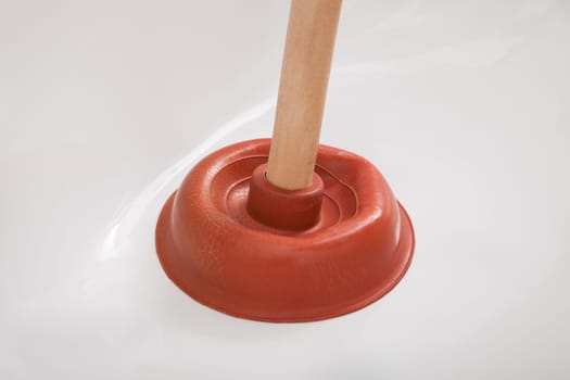 Portrait of male plumber pressing plunger in sink