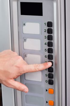 Close-up of hand pressing button of vending machine