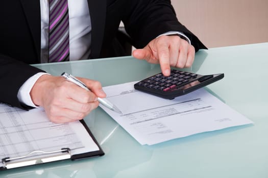 Portrait of happy businessman calculating finances in office
