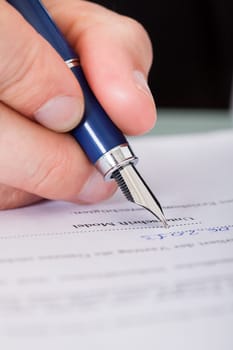 Close-up Of Businessman Hand Writing With Ink Pen Over Document