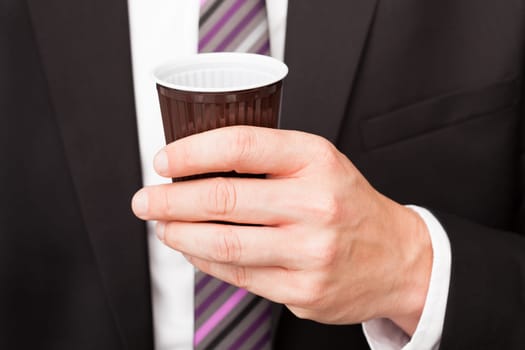 Portrait of happy businessman drinking coffee standing near vending machine