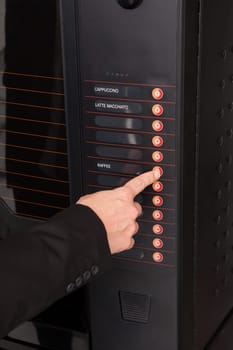Close-up of hand pressing button of vending machine for coffee