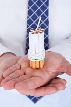 Close-up Of Businessman Holding Cigarettes Tied With Rope And Wick