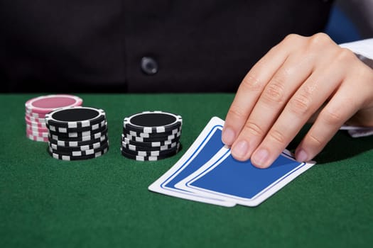 Close-up of a hand of poker player with cards and chips