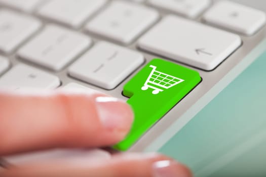 Close-up Of Hand Over Shopping Cart Symbol Button On Keyboard