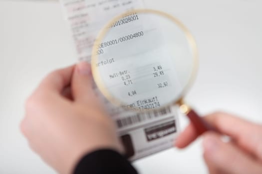 Close-up of businesswoman looking at check trough the loupe