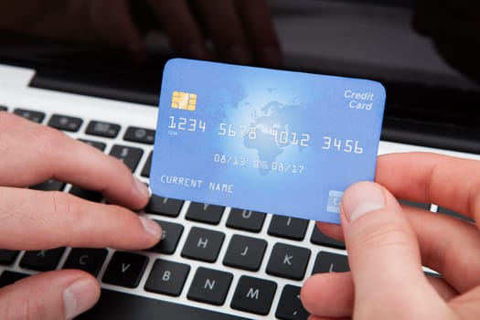 Man Shopping Online From Home Using Credit Card And Laptop